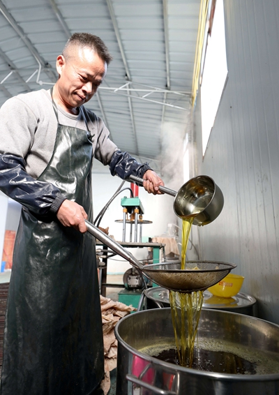 11月30日，在三江侗族自治县独峒镇林略村，一名村民在过滤茶油。.jpg