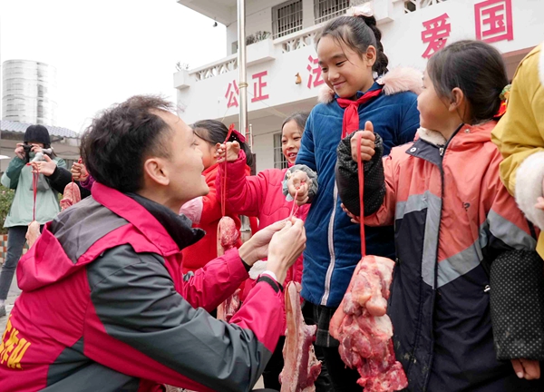 1月21日，在三江侗族自治县独峒镇知了小学，驻村第一书记在给获奖学生发猪肉。梁秀明 摄.jpg