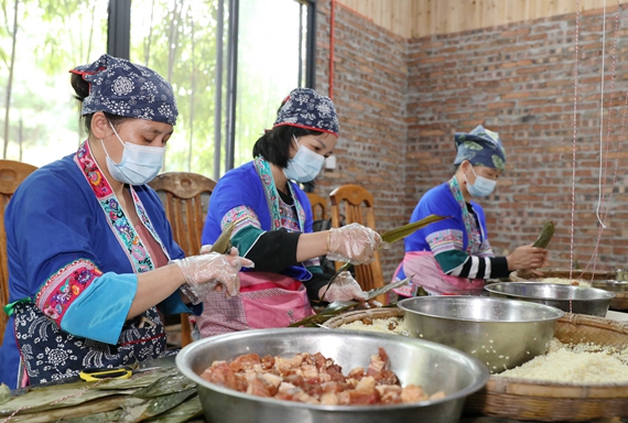 5月15日，在三江侗族自治县斗江镇牙林村盛龙风情园，几名妇女在包粽子。7.jpg