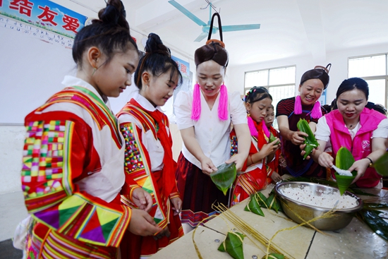 图3：融水县白云乡志愿者与林城村瑶族妇女孩子们一起包粽子共度六一.jpg